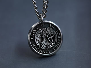 Titanium pendant with angelic design and 'St Michael Protect Us' text on a dark background
